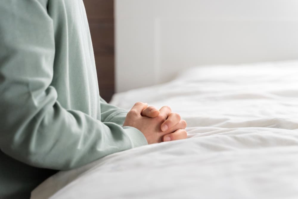 침대에 앉아 두 손을 모으고 심호흡하는 모습 — 자율신경 균형 회복을 위한 복식호흡 수족냉증 생활습관 관리